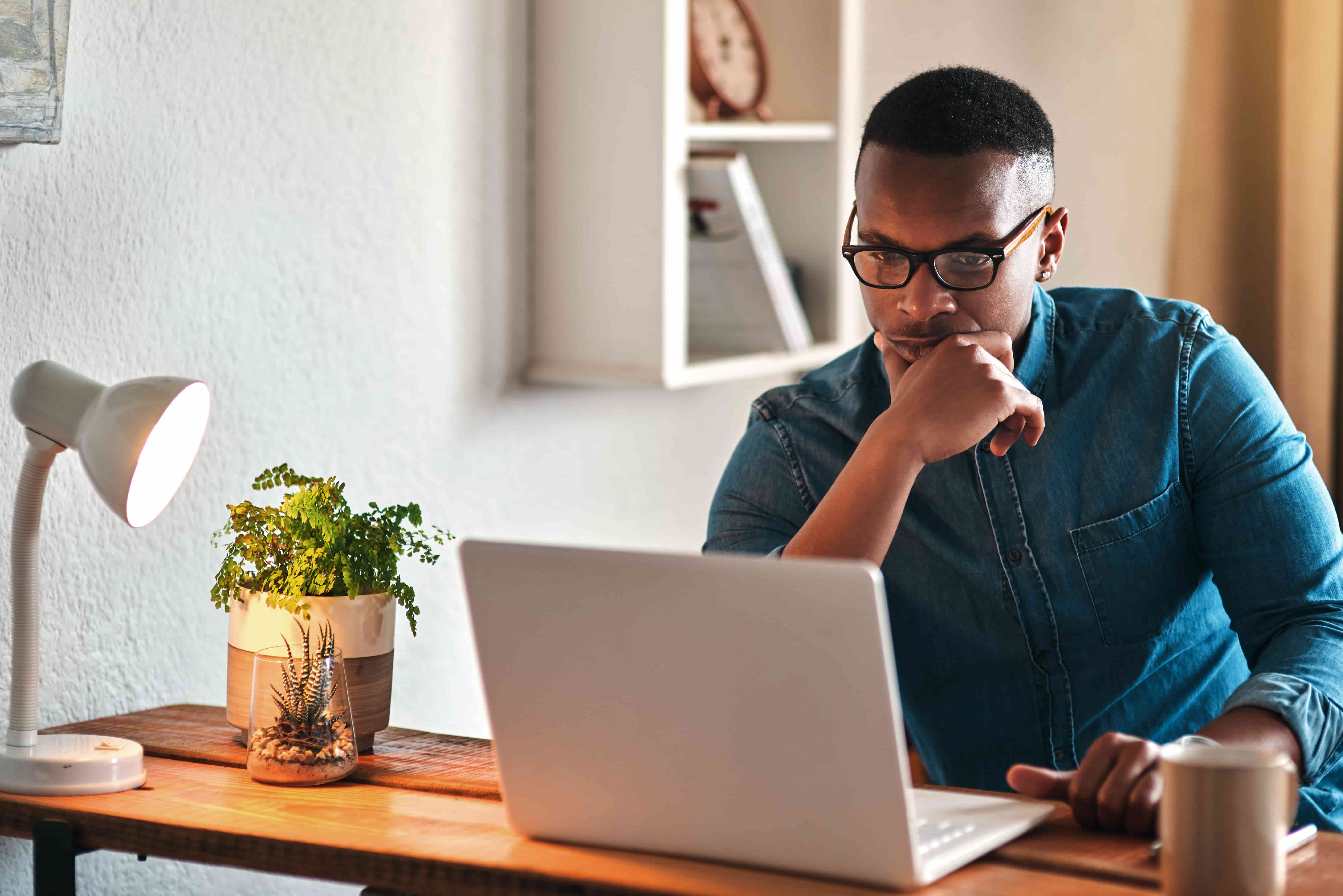 I wonder what I should do here. Cropped shot of a handsome young businessman sitting in his home office and looking contemplative while working on his laptop.